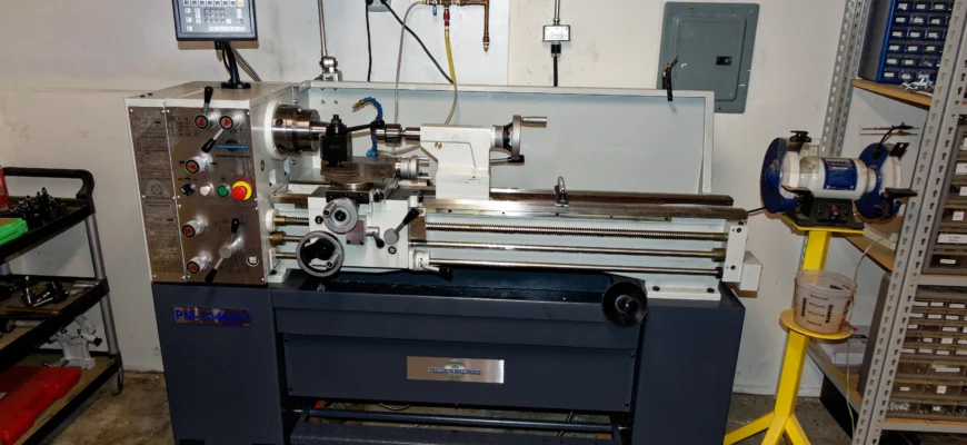 A benchtop metal lathe machining a steel part in a home workshop garage